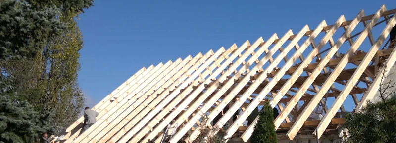 Helle Dachsparren einer Holzkonstruktion vor blauem Himmel